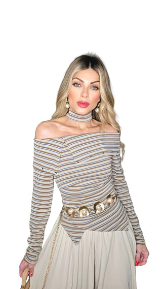 Woman wearing a striped off-shoulder top and pleated skirt indoors.